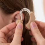 Une dame à qui le médecin insère l'appareil auditif dans l'oreille