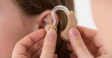 Une dame à qui le médecin insère l'appareil auditif dans l'oreille