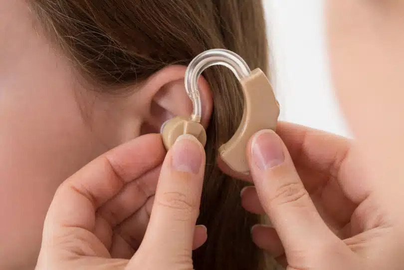 Une dame à qui le médecin insère l'appareil auditif dans l'oreille